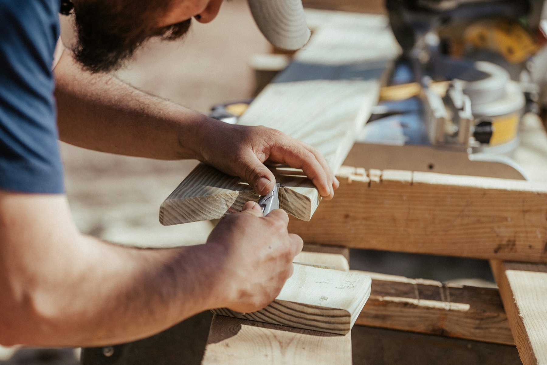 Hände führen einen Hobel über ein Holzbrett
